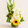White lilies and yellow sunflowers in a glass vase
