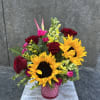 Bouquet of sunflowers, red roses, and pink flowers in a pink vase