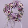 Lavender and white floral wreath on a stand with trailing greenery