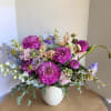 Mixed bouquet of purple, pink, and blue flowers in a white vase