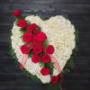 Heart-shaped white floral arrangement with red roses and a red ribbon