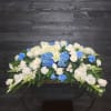 Casket Spray only. Blue delphinium, white lilies and other seasonal blooms. Approximately