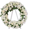 White floral wreath on a stand with roses and hydrangeas