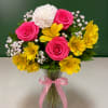 Pink roses, white carnation, and yellow alstroemeria in a glass vase with a pink ribbon