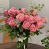 Pink roses arranged in a clear glass vase with greenery