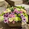 A lush blend of roses, carnations, and daisies in soft pastels and