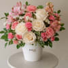 Pink and cream flower arrangement in a white pot