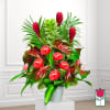 Tropical arrangement with red anthuriums and red ginger in a white pot