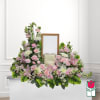 Pink and white floral funeral tribute around a framed photo