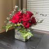 Red roses arranged in a clear square glass vase
