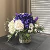 Purple and white floral arrangement in a clear glass vase