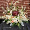 Low floral arrangement with white lilies, peach roses, and white daisies in a burgundy vase