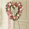 Heart-shaped floral wreath on an easel with pink and white flowers