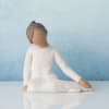 Small seated figurine in a white dress against a blue background