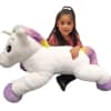 Girl hugging a large white unicorn plush toy with rainbow accents