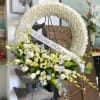 White floral funeral wreath with a ribbon reading 