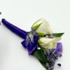 A boutonniere  featuring white spray roses, dark purple larkspur, purple filler