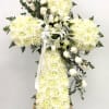 White floral cross arrangement on an easel with lilies and roses