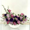 Pink and lavender roses arranged in a white bowl vase