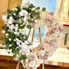 A heart-shaped wreath of soft pastels and white Phalaenopsis orchids creates an