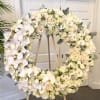 A large circular sympathy wreath arranged with creamy white and soft pink