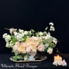 Pastel floral arrangement in a white vase with a lit candle beside it