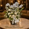 White orchids and roses arranged in a low bowl on a marble table