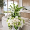 White and green floral arrangement in a white vase on a table