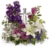 Purple and white floral arrangement with a silver cross centerpiece
