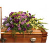 Purple and lavender floral spray on a wooden casket