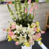 Pink tulips, white lilies, and roses in a tall white vase