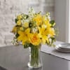 Bright yellow roses and lilies with white stock and greenery in a
