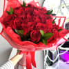 Hand-tied bouquet of red roses wrapped in red paper with a matching ribbon