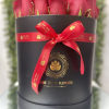 Round black hatbox filled with red roses and tied with a red ribbon bow