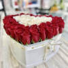 Heart-shaped white box filled with red roses around a cluster of white roses in the center