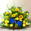 Low basket arrangement with yellow roses, gerberas, blue hydrangeas and white flower spikes