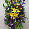 Tall standing spray of yellow lilies, roses, and purple blooms on a metal easel