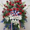 Tall red, white, and blue standing spray with roses, carnations, lilies, and ribbon on an easel