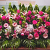 Large pink and white floral arrangement with roses, lilies, hydrangeas and gerberas in a low, wide display