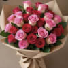 Large bouquet of red and pink roses wrapped in tan paper with a tied ribbon