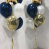 Two balloon bouquets with gold star balloons, navy and white balloons, and confetti balloons