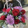 Basket of red roses and purple daisies with a white handle