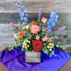 Mixed arrangement of pink roses, blue delphinium, and red mum in a wooden cube vase