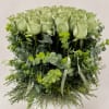 Arrangement of pale green roses in a white vase with trailing greenery