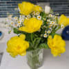 Yellow tulips and white daisies in a clear glass vase