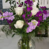 White roses and purple flowers arranged in a clear glass vase