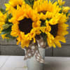 Bouquet of bright yellow sunflowers in a metal bucket with a polka-dot ribbon