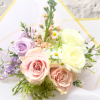 Bouquet of pastel roses and small daisies wrapped in white paper