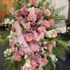 Large pink and white funeral spray with roses and lilies on a stand