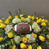 Yellow roses and pale hydrangeas arranged around a football centerpiece